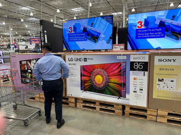 A shopper considers large-screen televisions on display in a Costco warehouse